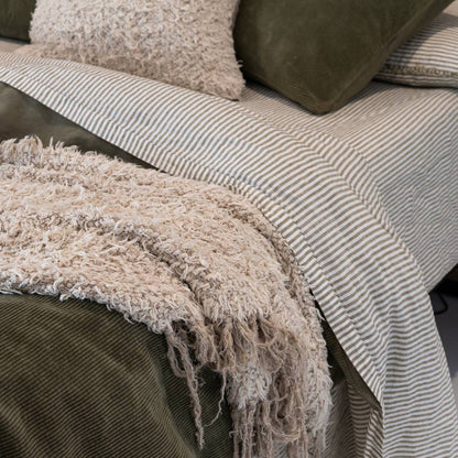 Dark green comforter on a bed in a bedroom with abstract art and decor.