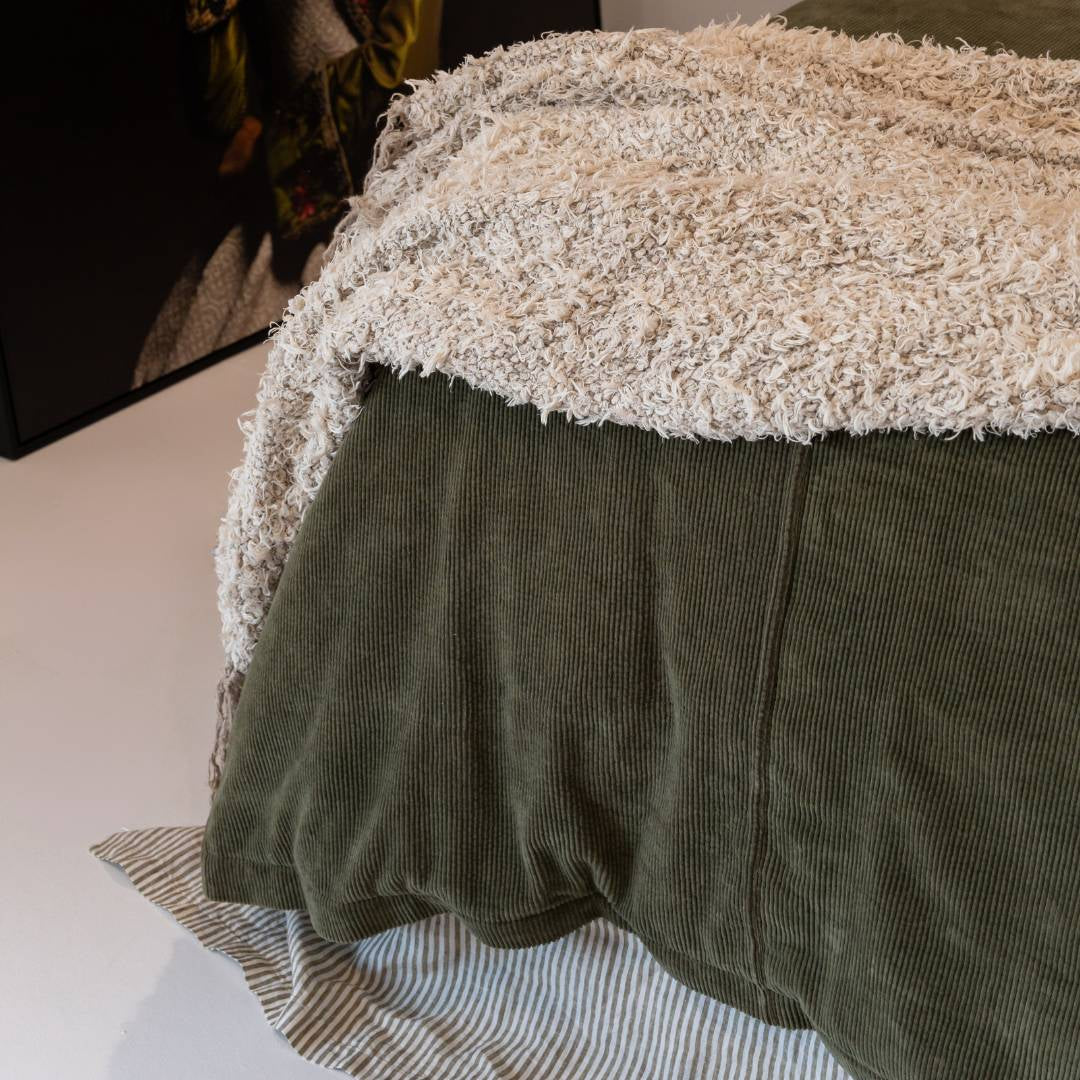 Dark green comforter on a bed in a bedroom with abstract art and decor.