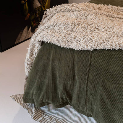 Dark green comforter on a bed in a bedroom with abstract art and decor.