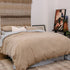 Beige comforter on a bed in a bedroom with abstract art and decor.