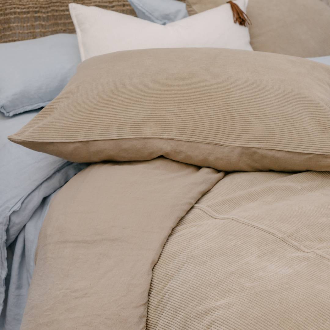Close-up of beige textured bedding with pillows on a bed.