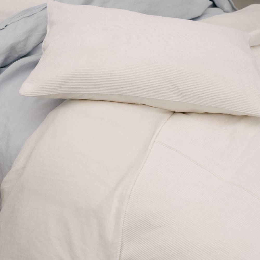 Close-up of white cord bedding with a pillow on a bed.
