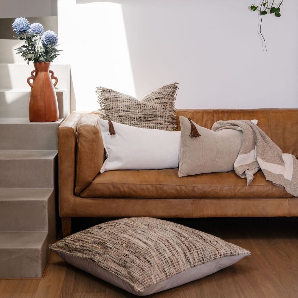 Wool and corduroy cushions by Eadie Lifestyle styled on a leather sofa in a New York style loft in a home setting.