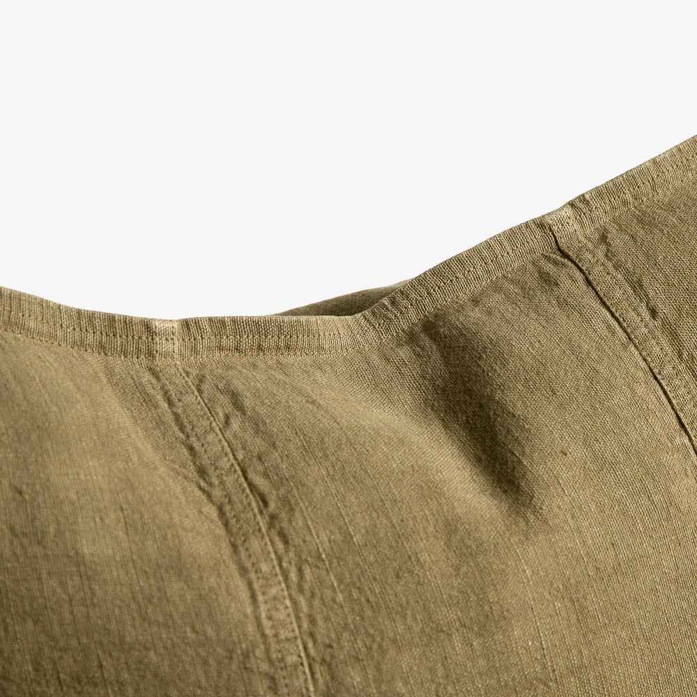 Close-up of a textured olive green fabric garment, showing the waistband and stitching details against a plain white background.