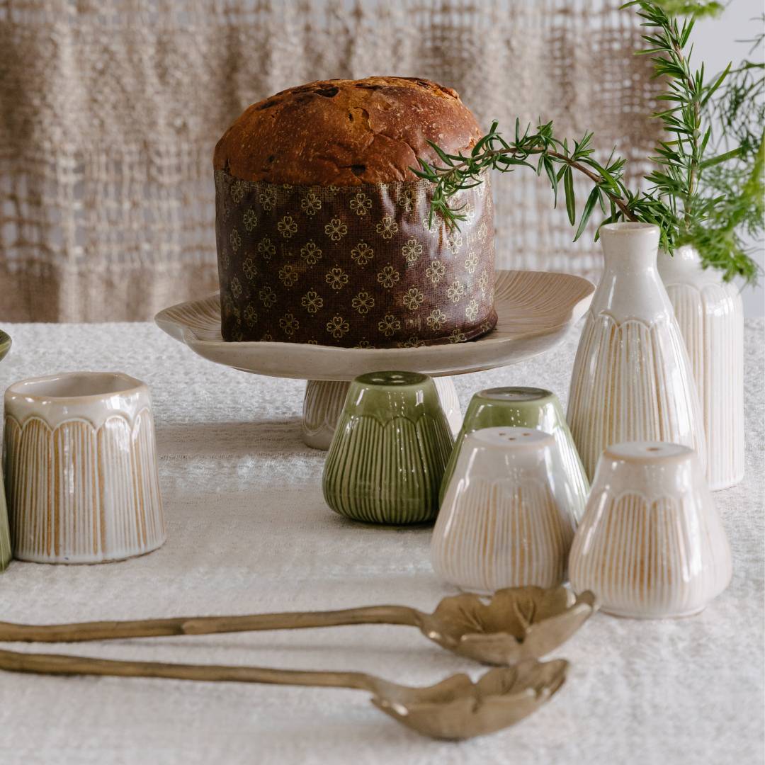 Decorative table setting with a loaf of bread, ceramic vases, and spoons on a textured surface.