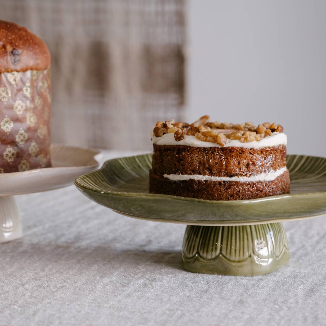 Two-layered cake with walnuts on a green ceramic cake stand.