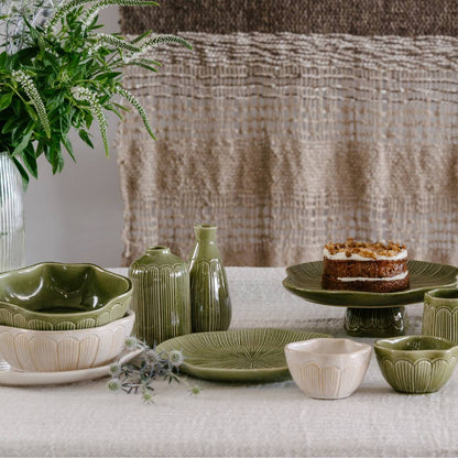 Green ceramic tableware set on a light surface with a textured fabric background