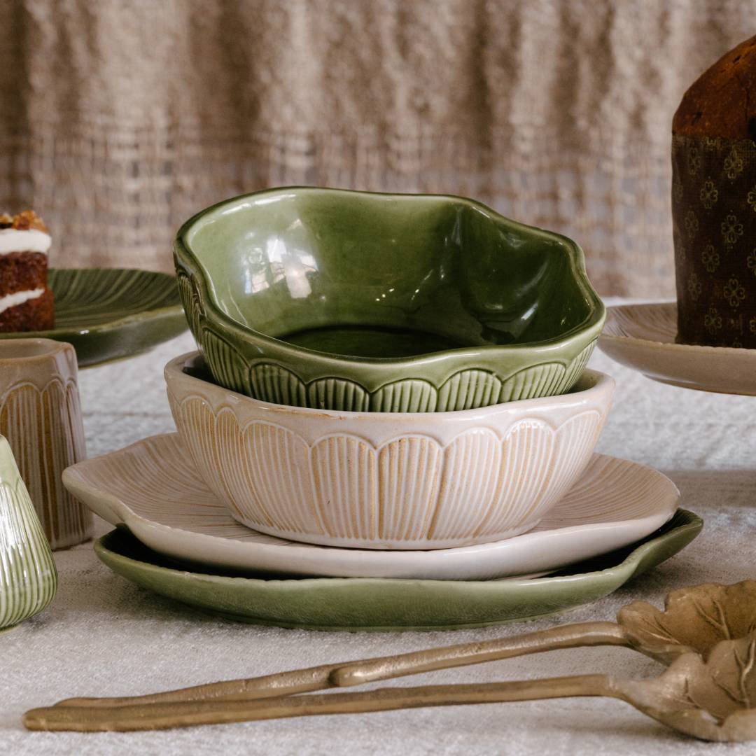 Set of ceramic bowls and plates with a decorative spoon on a textured surface