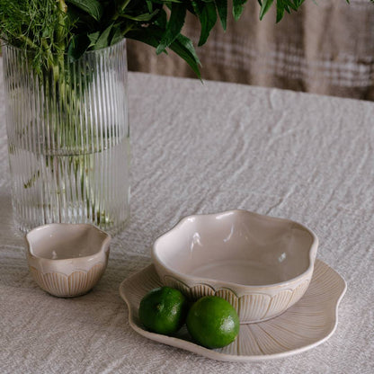 Ceramic bowls with limes on a textured tablecloth, vase with greenery in the background