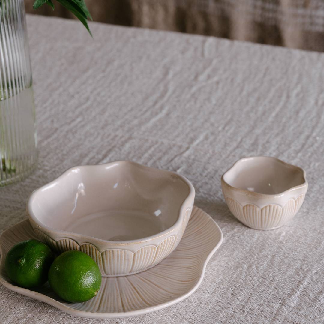 Two ceramic bowls on a textured surface with limes beside them