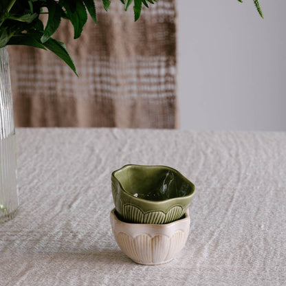 Two stacked ceramic pots with a textured surface on a light fabric background.