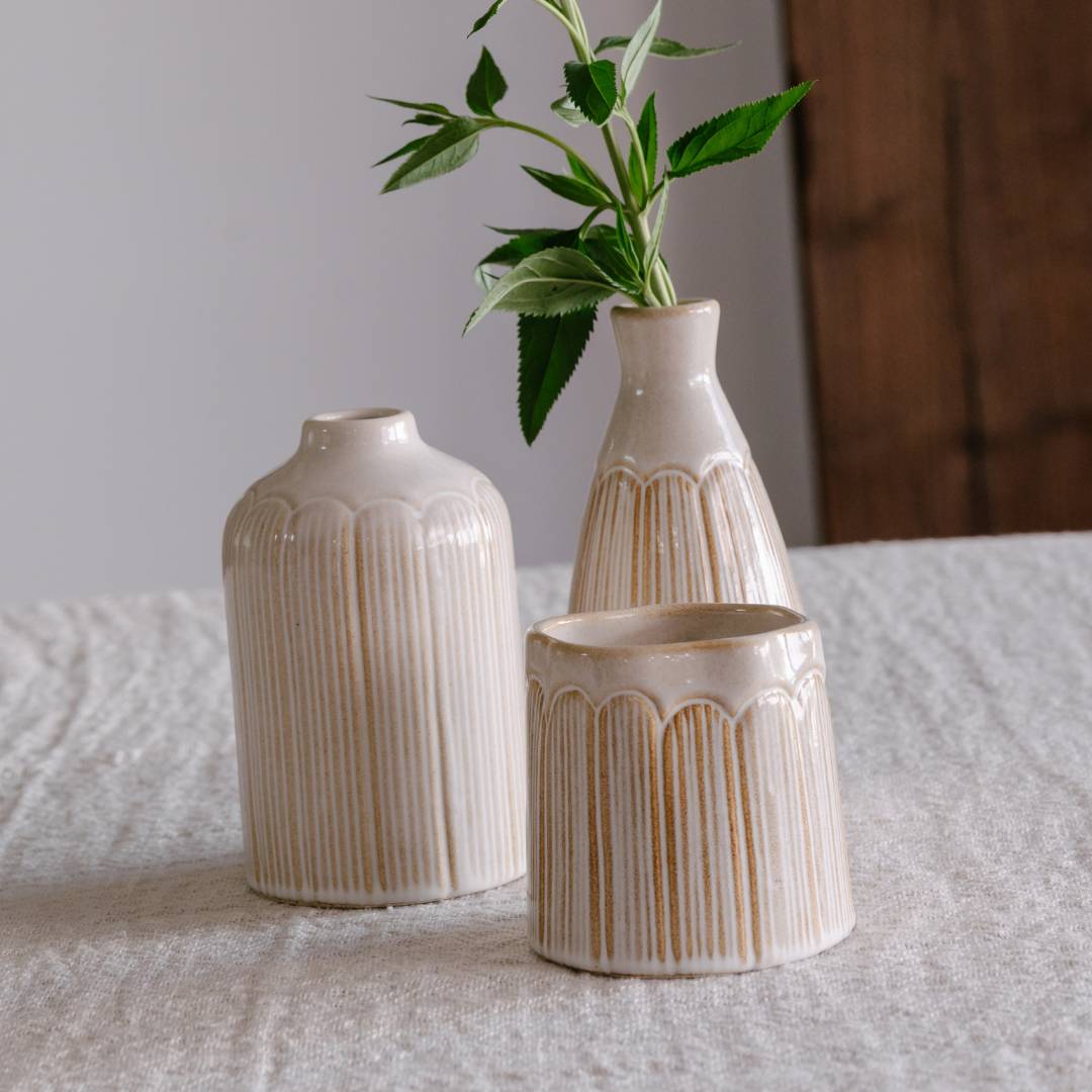 Three ceramic vases with textured design on a tablecloth.