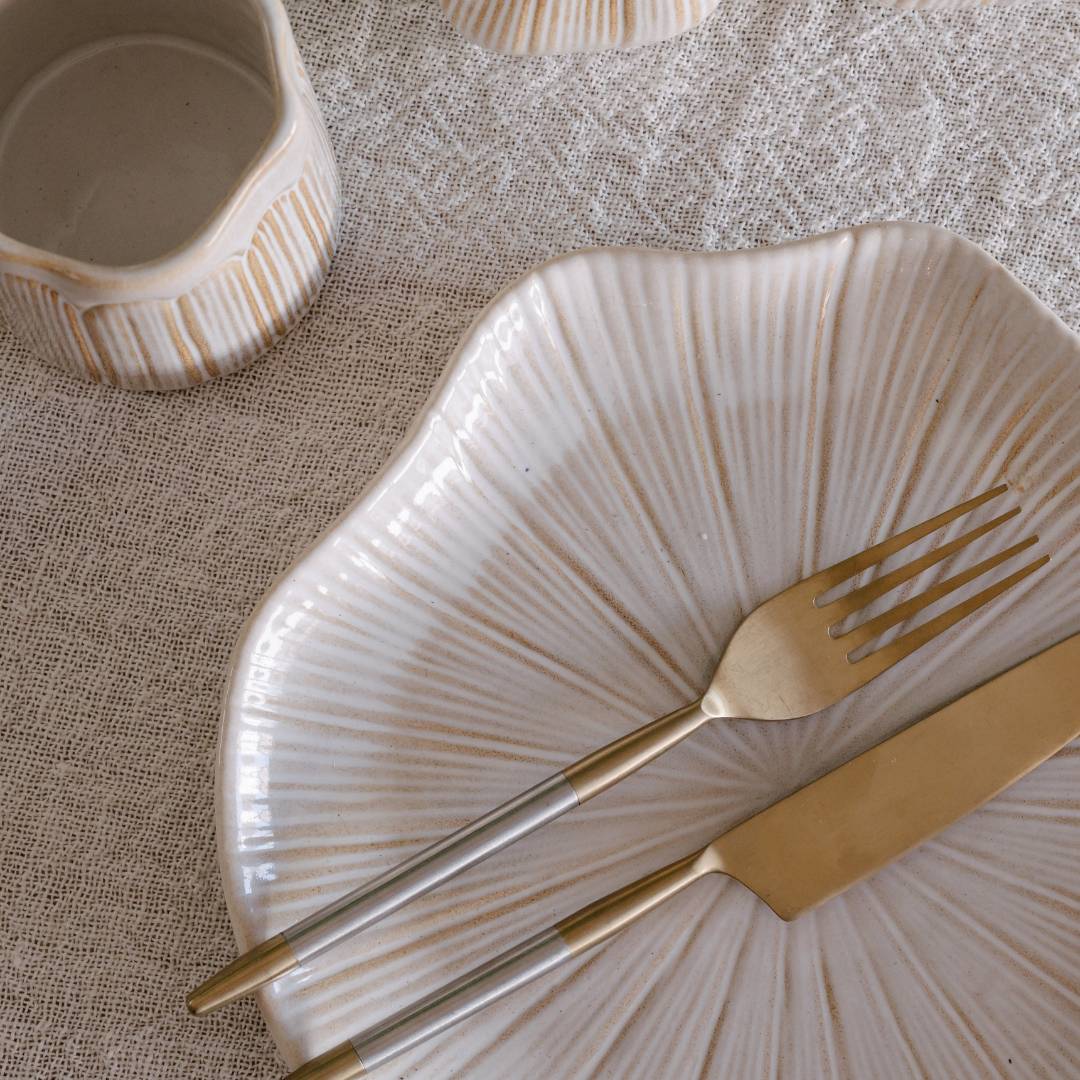 Decorative plate with gold fork and knife on a textured surface
