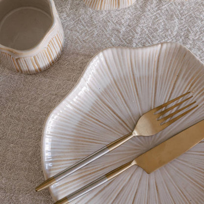 Decorative plate with gold fork and knife on a textured surface