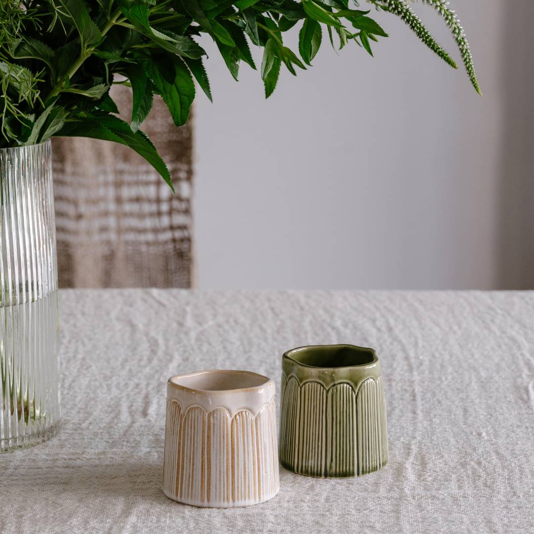 Two ceramic planters on a textured surface with a blurred background