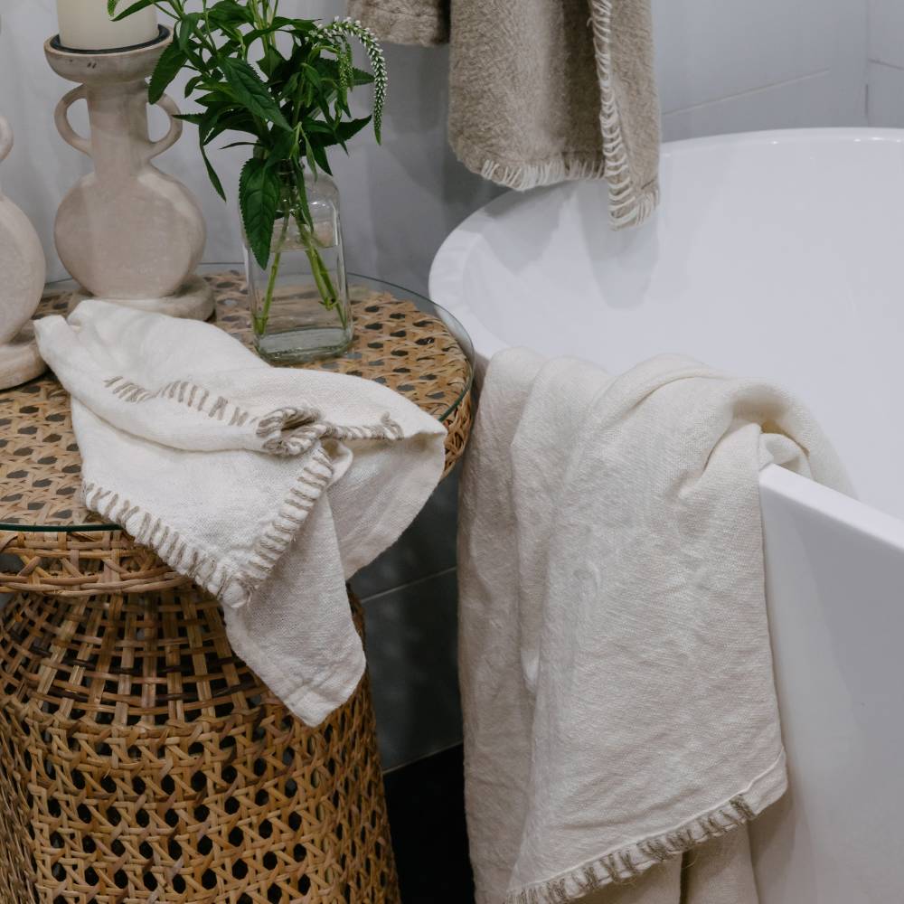 Bathroom setting with towels, a plant, and a candle.