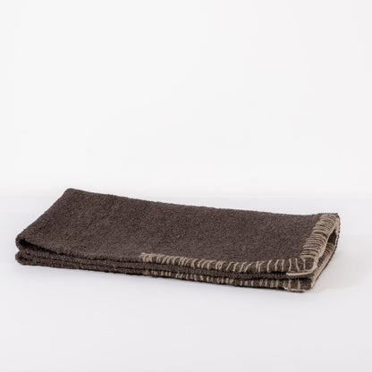 A dark brown woven bathmat on a white background