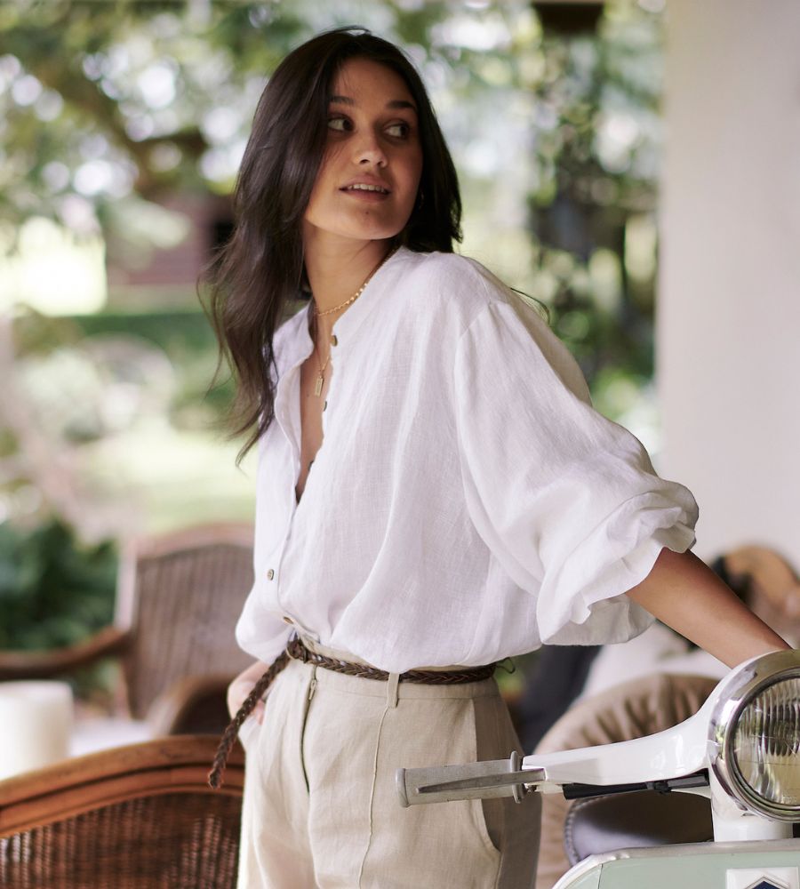 white linen button up blouse with puff sleeves paired with tailored pants and brown leather belt