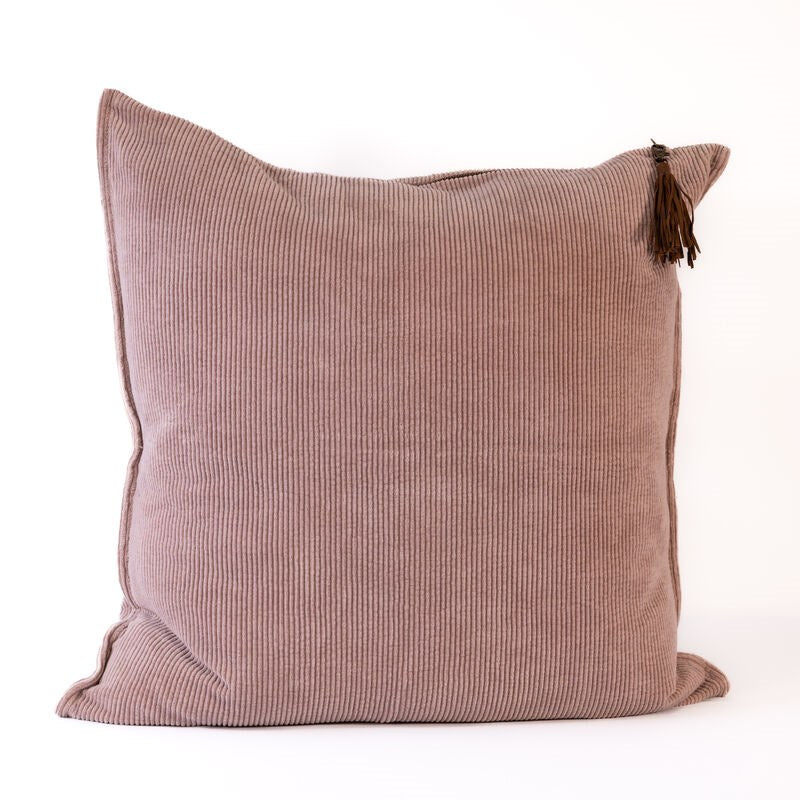 Pink textured pillow with a tassel on a white background